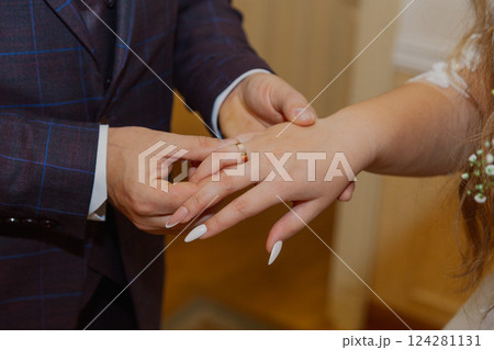 A young groom puts a gold wedding ring on his 124281131