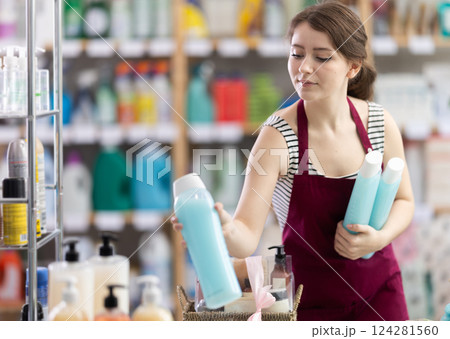 Young woman seller puts shampoo and shower gel 124281560