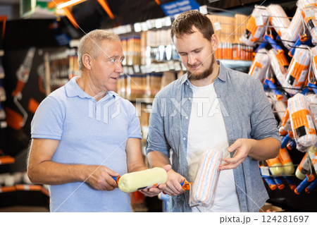Elderly and young men choosing paint roller in store Elderly and young men choosing paint roller in store 124281697