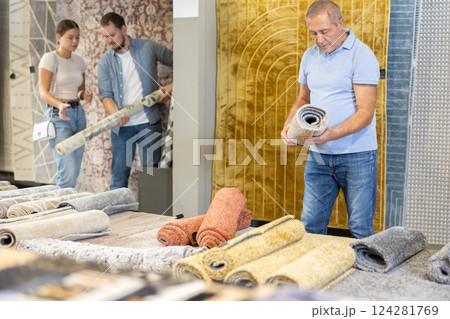 On territory of exhibition hall, senior man inspect carpets On territory of exhibition hall, senior man inspect carpets 124281769