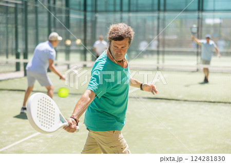 Padel game - man with partners plays on court Padel game - man with partners plays on court 124281830