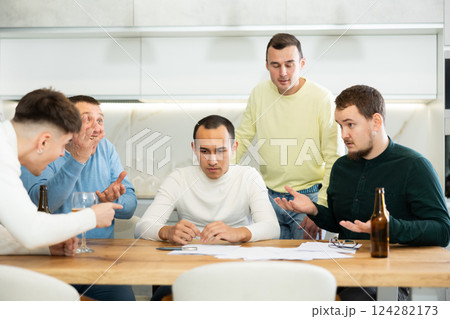 Brainstorming - male friends drinking beer and trying to solve financial problems by consulting each other while sitting at table 124282173