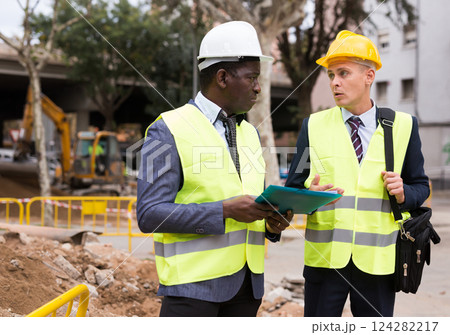 Two engineers talking about road repairing works documentation Two engineers talking about road repairing works documentation 124282217