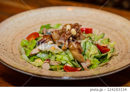 Salad with meat and nuts on a plate on a wooden 124283134