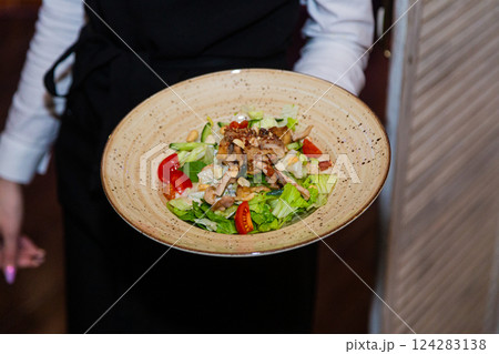 Salad with meat and nuts on a plate in the hands 124283138