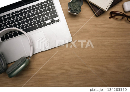 Creative workspace with laptop, headphones, notebook, and glasses. 124283550