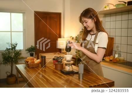 Smiling young woman preparing fresh coffee in a cozy home kitchen 124283555