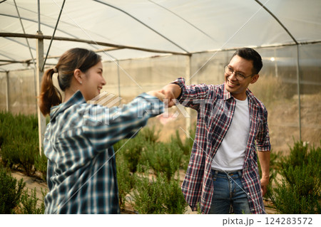 Happy asian farmers sharing a fist bump in a greenhouse farm 124283572