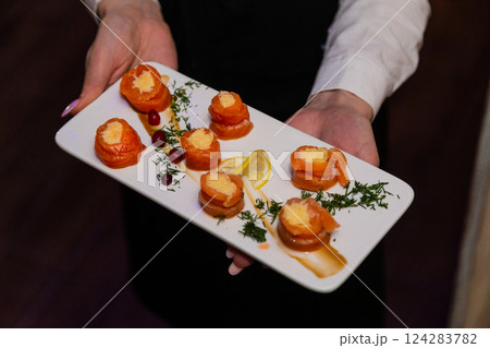 Appetizing fish rolls in the hands of a waiter on 124283782
