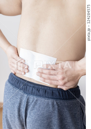 腰に湿布を貼る男性　腰痛　湿布　筋肉痛 124284575