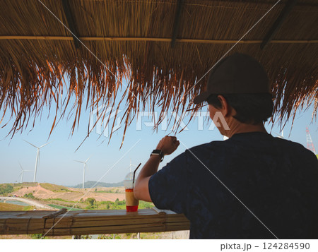 solo traveler man sit and drink coffee at counter bar with wind turbine background solo traveler man sit and drink coffee at counter bar with wind turbine background 124284590