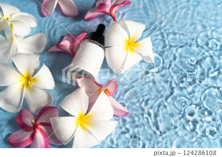 Moisturizing serum surrounded by fresh plumeria blooms creates a serene spa atmosphere. Moisturizing serum surrounded by fresh plumeria blooms creates a serene spa atmosphere. 124286108
