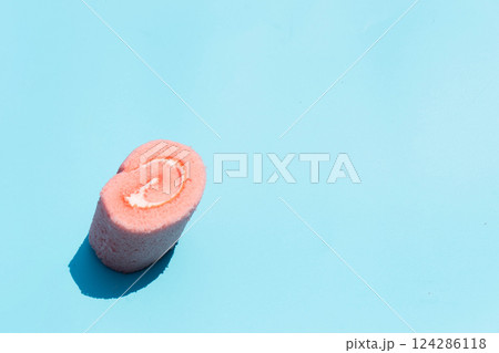 A pink cupcake with a rose sits on a bright blue background, adding cheer. 124286118