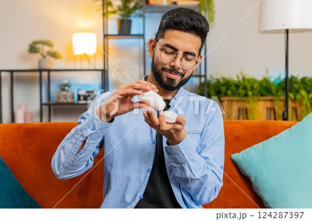 Indian ill sick man taking medicine antibiotic pill with water at home sofa health care pharmacy Indian ill sick man taking medicine antibiotic pill with water at home sofa health care pharmacy 124287397