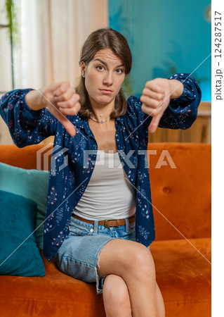 Upset unhappy young woman showing thumbs down sign dislike gesture disapproval bad work feedback 124287517