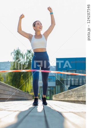 Athletic fitness sport runner woman finishing racing competition celebrating victory in city park 124287546