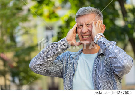 Displeased man rubbing temples to cure headache problem suffering from migraine stress on street Displeased man rubbing temples to cure headache problem suffering from migraine stress on street 124287600