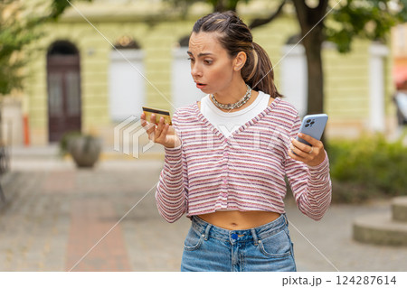 Shocked woman trying pay online shopping with smartphone blocked credit card lack of money balance Shocked woman trying pay online shopping with smartphone blocked credit card lack of money balance 124287614