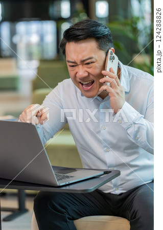 Angry young businessman CEO in shirt making smartphone online conversation call in office lobby Angry young businessman CEO in shirt making smartphone online conversation call in office lobby 124288826