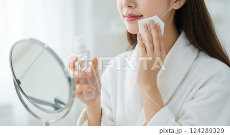 鏡を見てスキンケアをする女性の手元 124289329