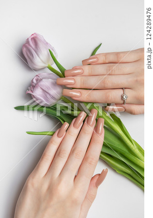 Woman showing nude manicure and purple tulips on white background Woman showing nude manicure and purple tulips on white background 124289476