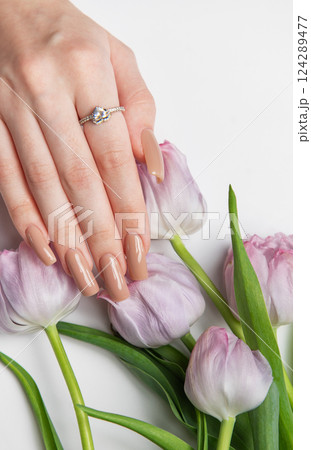 Woman showing beige manicure near bouquet of purple tulips Woman showing beige manicure near bouquet of purple tulips 124289477