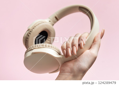 Woman holding wireless headphones on pink background 124289479
