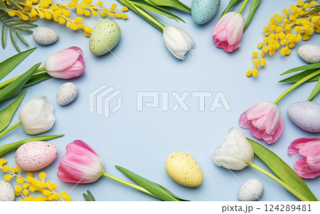Easter eggs and tulips forming a frame on light blue background 124289481