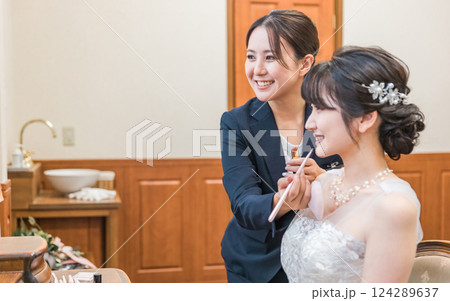 ブライズルーム・控え室で花嫁・新婦にメイクをするブライダルヘアメイクアーティストの女性（リップ） 124289637