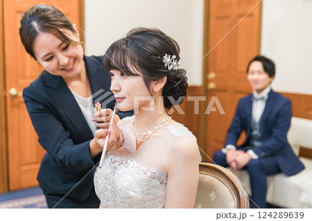 ブライズルーム・控え室で花嫁・新婦にメイクをするブライダルヘアメイクアーティストの女性（リップ） 124289639