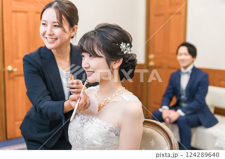 ブライズルーム・控え室で花嫁・新婦にメイクをするブライダルヘアメイクアーティストの女性（リップ） 124289640