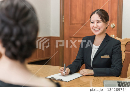 コンシェルジュ・ホテリエ・ウェディングプランナーと打ち合わせ・契約する女性（結婚相談所） 124289754