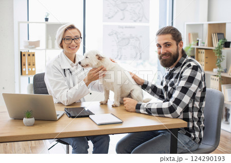 Veterinarian woman with young man and dog in veterinary clinic. Female doctor with male pet owner interacting, patient examination. Veterinarian woman with young man and dog in veterinary clinic. Female doctor with male pet owner interacting, patient examination. 124290193