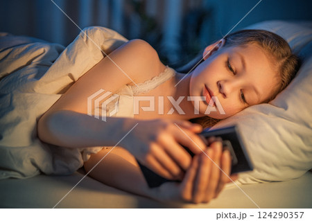 girl with phone in the bed 124290357