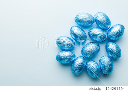 Chocolate easter eggs wrapped in blue colored foil on blue background. Chocolate easter eggs wrapped in blue colored foil on blue background. 124291394