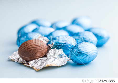 Chocolate easter eggs wrapped in blue colored foil on blue background. 124291395