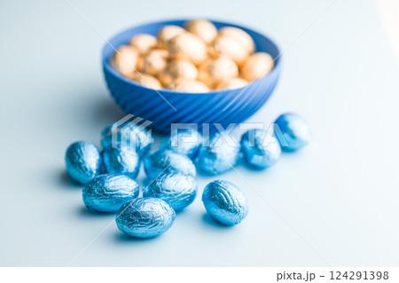Chocolate easter eggs wrapped in blue colored foil on blue background. 124291398