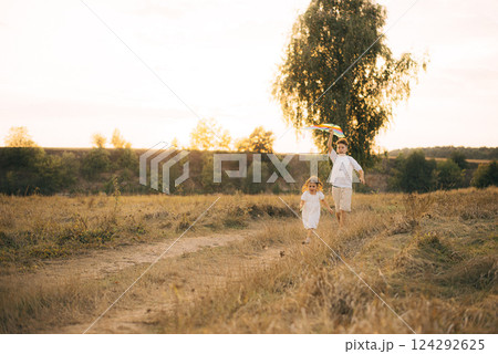 Older brother and sister running with a kite 124292625