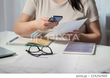 Woman paying bills online using smartphone at home. Bill paying concept. Digital payment using internet banking and qr code 124292900