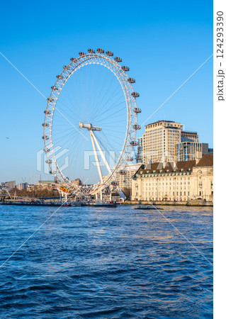 The London Eye stands tall against a clear blue sky, offering stunning views of the river and city skyline. Visitors enjoy a unique perspective of London from the cantilevered observation wheel. The London Eye stands tall against a clear blue sky, offering stunning views of the river and city skyline. Visitors enjoy a unique perspective of London from the cantilevered observation wheel. 124293390