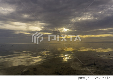Sunset over calm waters with reflections and dramatic clouds 124293512