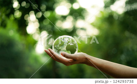 Environment and green world Green glass globe on hand green bokeh background Environment and green world Green glass globe on hand green bokeh background 124293738