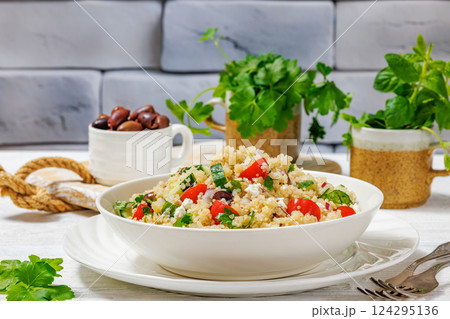 quinoa salad with veggies, cheese, olives in bowl 124295136