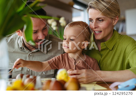 Family decorating easter eggs at home. 124295270