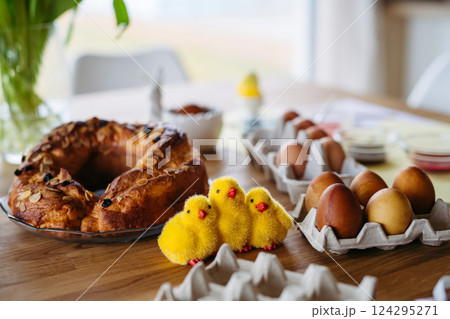 Traditional Easter table with dyed eggs, festive sweet bread and decorative chicks. 124295271