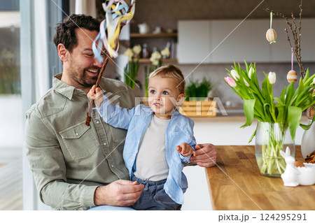 Father and little boy holding easter whip from willow branches, decorated with ribbons. 124295291