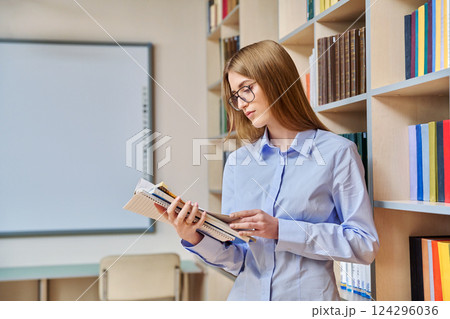 Portrait of student teenager girl holding textbooks inside classroom library 124296036