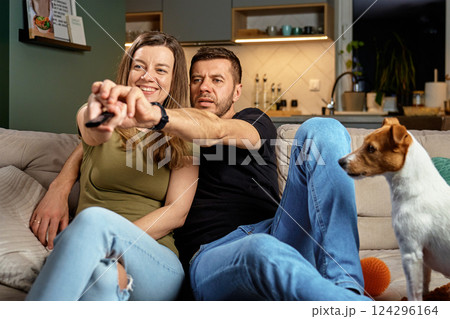 Man and woman relaxing on couch with dog, watching television 124296164