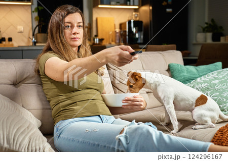 Woman watching TV while dog steals food from bowl 124296167