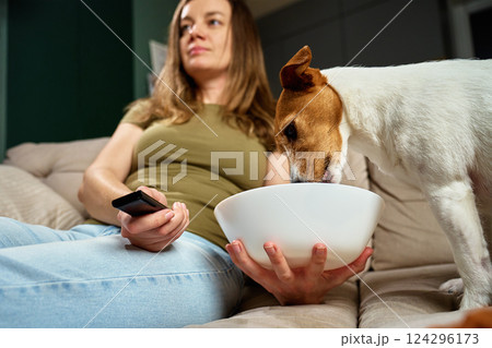 Woman watching TV while dog steals food from bowl Woman watching TV while dog steals food from bowl 124296173